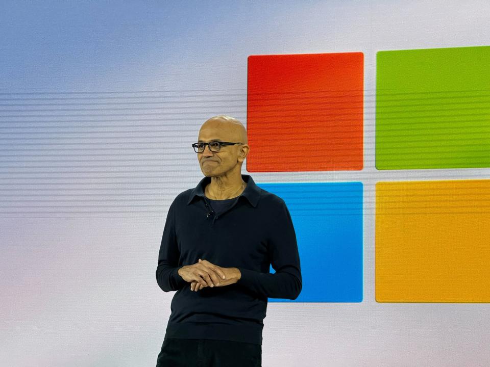 Microsoft CEO Satya Nadella on stage at the event in front of the Microsoft logo.