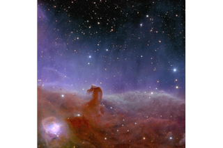 A lot of hazy looking reddish gas collects at the bottom of the screen and forms a small hook shape towards the left.  Above is a glow of purple light gradually fading into the top of the image, showing a dark region of space with star spots.