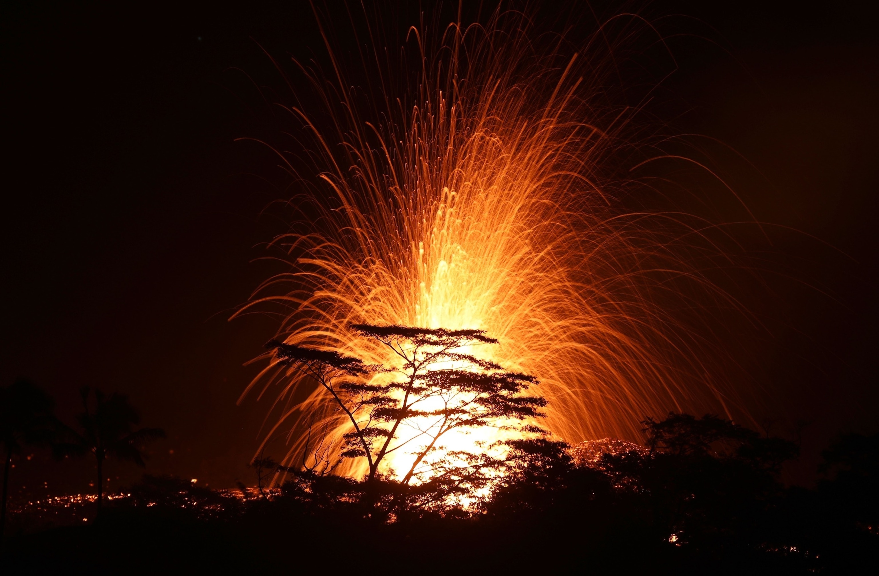 PHOTO: Lava is blurred as it erupts from the Kilauea volcano fissure above the treetops on Hawaii's Big Island on May 17, 2018 in Kapoho, Hawaii.