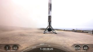 a white and black rocket rests on a concrete landing pad shortly after landing