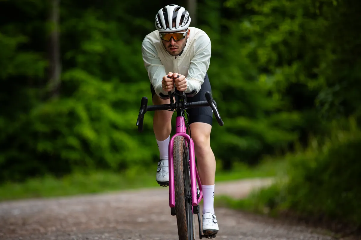 A man on aero extensions wearing a white cycling jacket