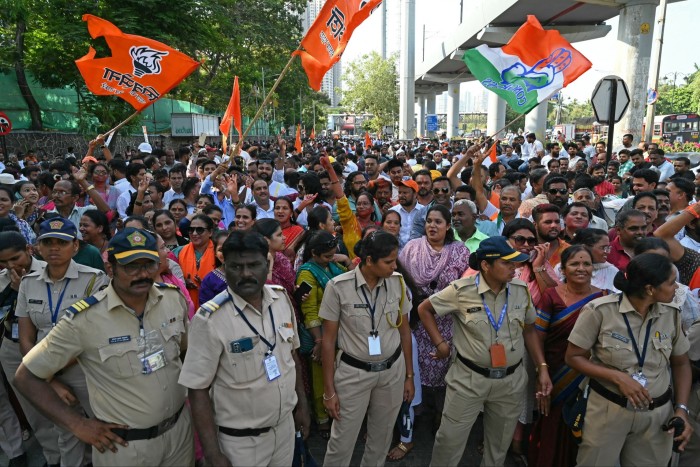 The crowd waves flags behind the police