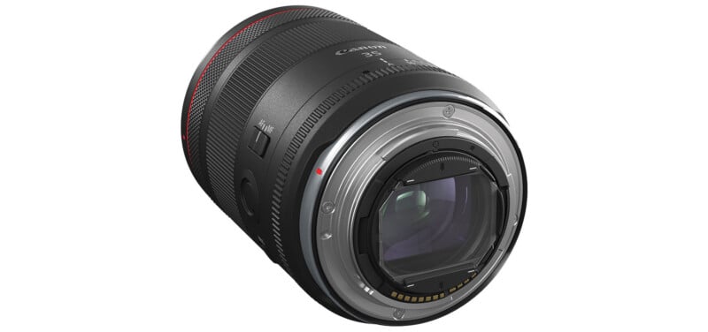 A close-up of a Canon camera lens.  The lens has various switches and markings and is mostly black with a red highlight ring on the end.  Internal glass elements and electronic contacts on the mounting side are visible.