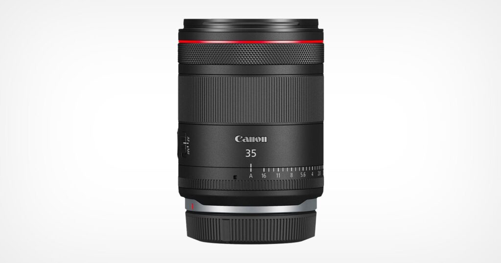 A Canon 35mm camera lens with a sleek black design. The lens features a red ring near the top, a focus adjustment ring, and a control ring. The brand name "Canon" and the number "35" are printed in white on the front. The background is plain white.