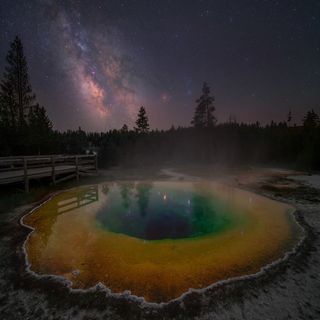 The Milky Way photographed above the morning glory hot spring in Yellowstone National Park, USA