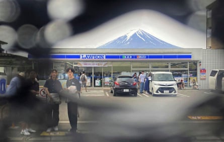 Mount Fuji can be seen through a hole in a black screen installed across from a convenience store in the town of Fujikawaguchiko.