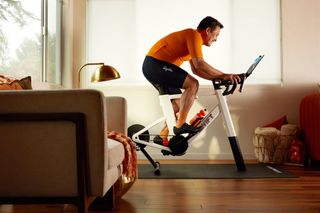 A man rides a Zwift Ride smart trainer in the living room