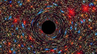 This computer-simulated image shows a supermassive black hole at the core of a galaxy.  The black area in the center represents the event horizon of the black hole, where no light can escape the massive object's gravitational grip.  A black hole's strong gravity warps the space around it like a funhouse mirror.  The light from the background stars is stretched and blurred as the stars pass through the black hole.