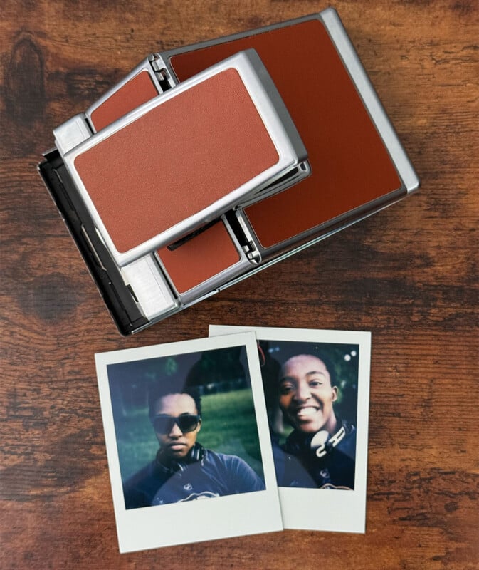 Vintage Polaroid camera with brown and silver design on wooden surface, complete with two instant film photos.  The photos show two smiling individuals, each wearing sunglasses and headphones.