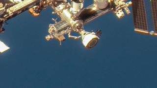 a cone-shaped spacecraft attached to a vast metallic space station