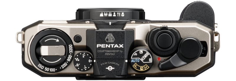 Top view of a Pentax film camera with various dials, shutter button and ISO setting range from 50 to 3200. The camera body is silver with black accents and the mark "Pentax" is prominently displayed in the center.