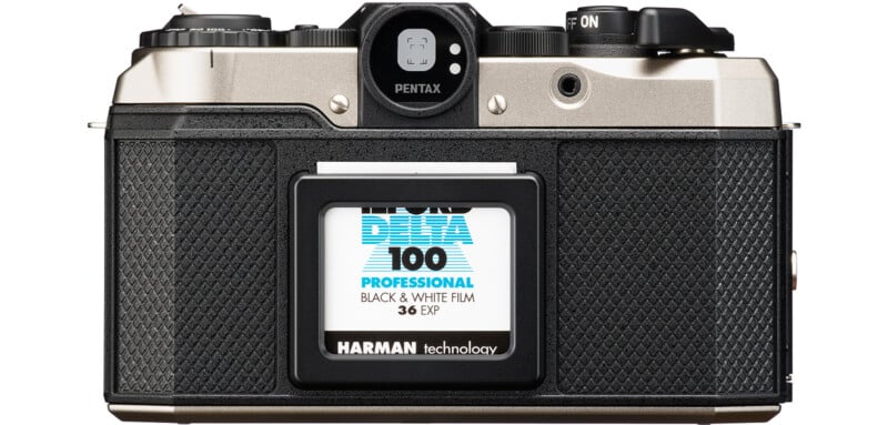 Vintage Pentax film camera with Ilford Delta 100 Professional black and white film roll inserted.  The camera has a textured black grip and a metal upper body with various buttons and dials visible on top.