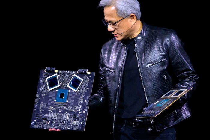 A man in a black leather jacket is holding a circuit board