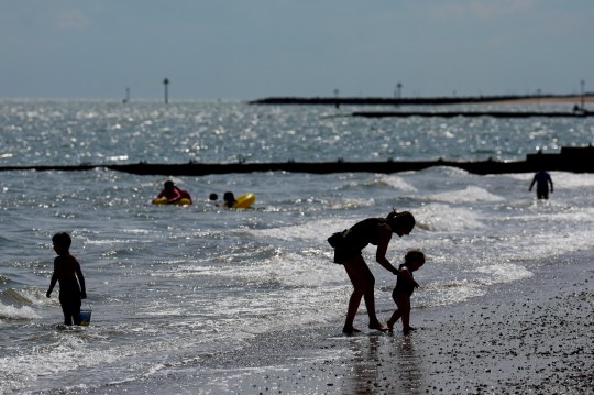 People enjoying the sunny weather, playing in the sea on a British beach