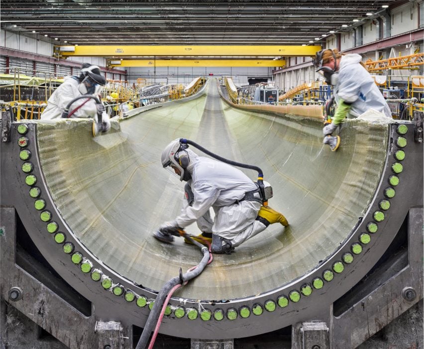 Grinding impregnated fiberglass inside a wind turbine blade casing.