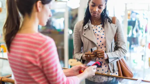 Getty Images A woman about to buy something using a debit or credit card in a store