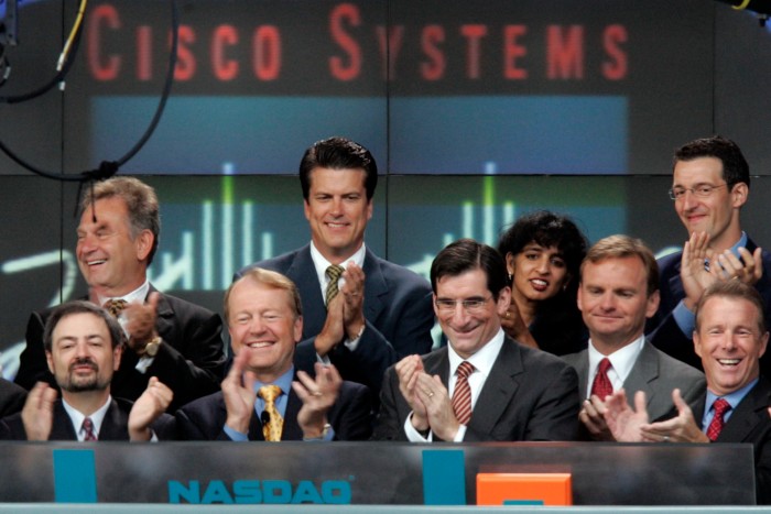 A group of executives stand under the Cisco sign on the Nasdaq trading floor