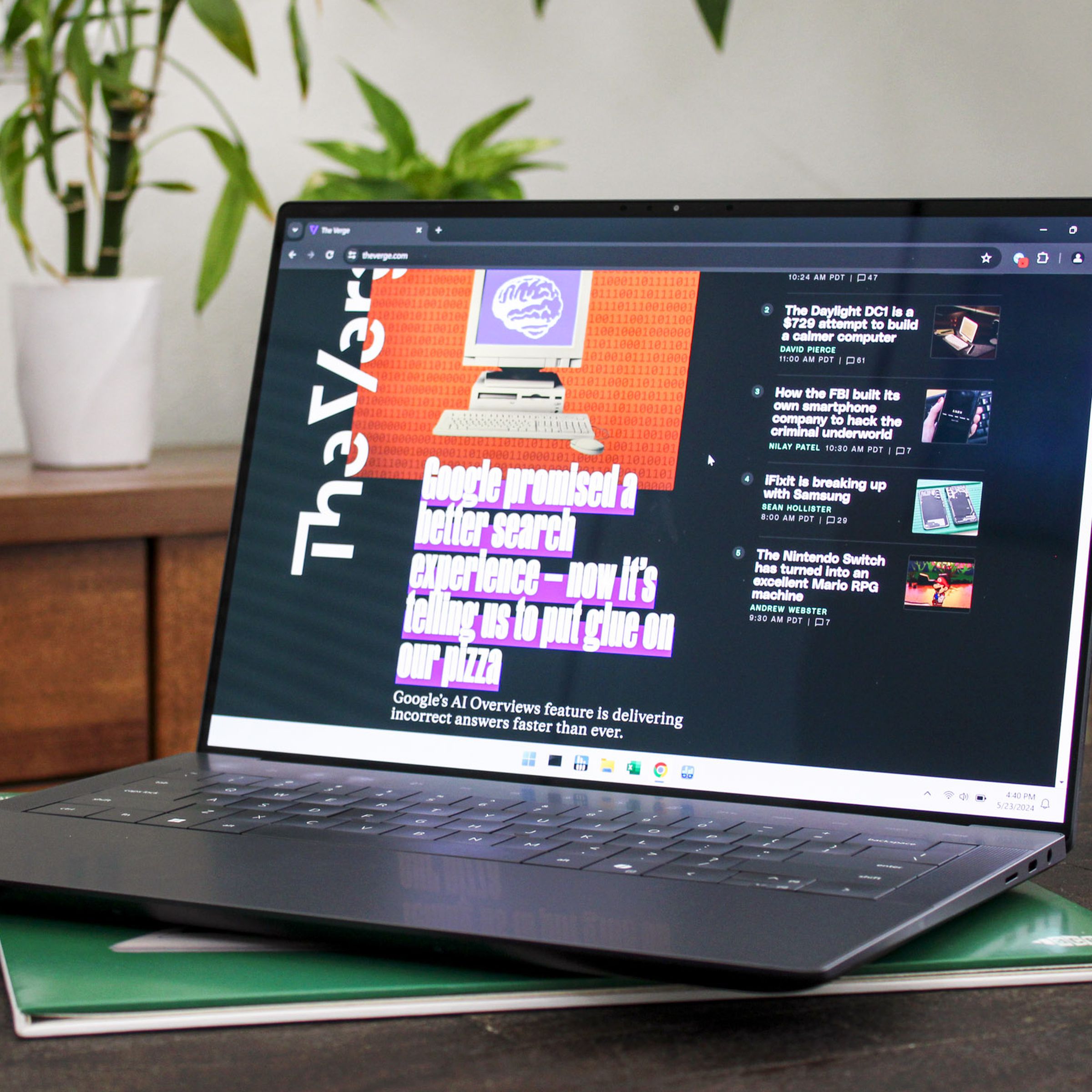 An open and switched on laptop sitting on a wooden table with plants and furniture in the background.