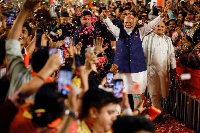 Modi waves as supporters throw confetti at the BJP headquarters