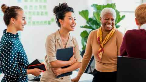 A diverse group of four colleagues have a lively and cheerful conversation in an office environment