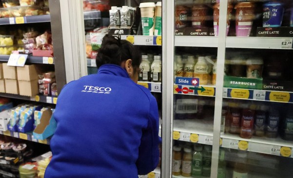 Tesco worker stacking fridge shelves 