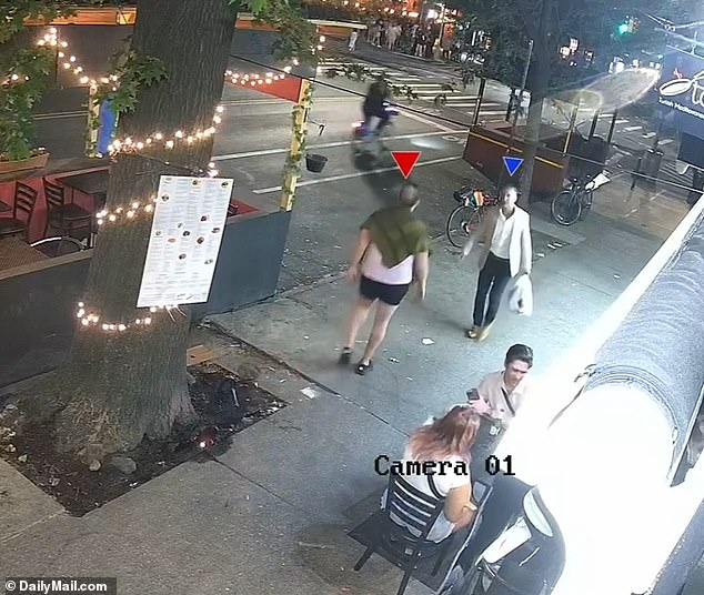 Kaye, 52, continues walking down the sidewalk, where she bumps into another member of the group (red arrow) and the two exchange words