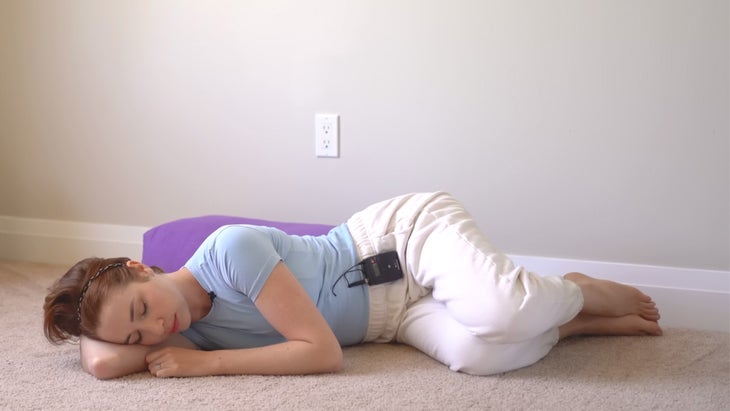 a woman practices yoga against a wall on her side