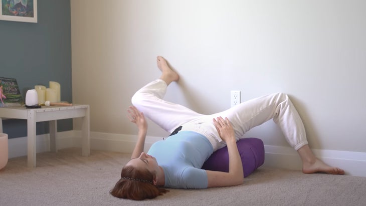 a woman practices yoga with her legs up the wall in different directions