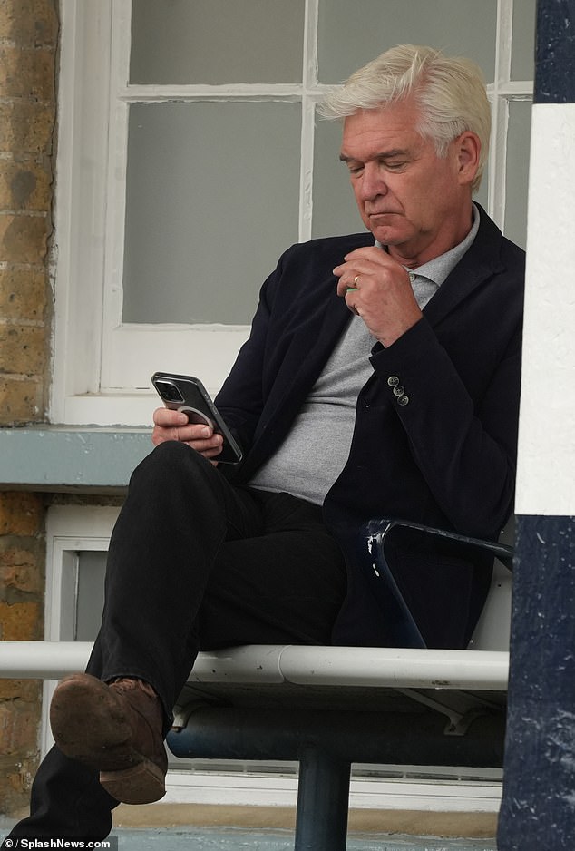 The former This Morning presenter, 62, puffed on a cigarette as he checked his phone while waiting for a train.