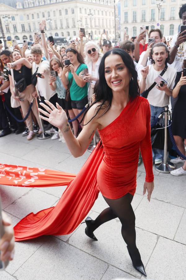 Katy Perry arrives at The Ritz Hotel in Paris in a red dress with black stockings and waves to fans