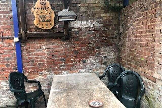 At the back is a small, walled smoking area, protected from the rain by a plastic roof