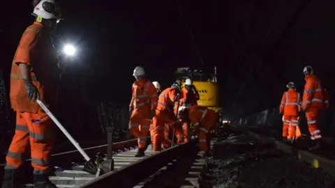 Network Rail workers in high-vis clothing are repairing the track in the Severn Tunnel