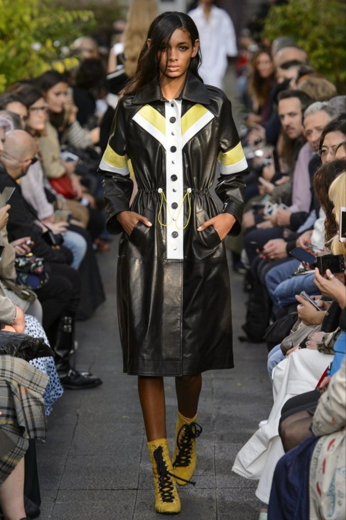 A model wears a black leather coat on the runway