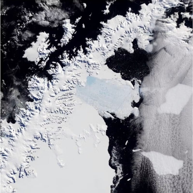 Satellite image showing mostly snow-covered land with dark waters and scattered glaciers visible.  On the left are darker patches of water interspersed with white ice formations, while the right side of the image is dominated by dense cloud cover.