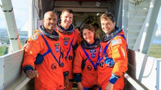 four astronauts in orange spacesuits gathered and standing with a smile on their shoulder to access the launch pad used for rocket launches