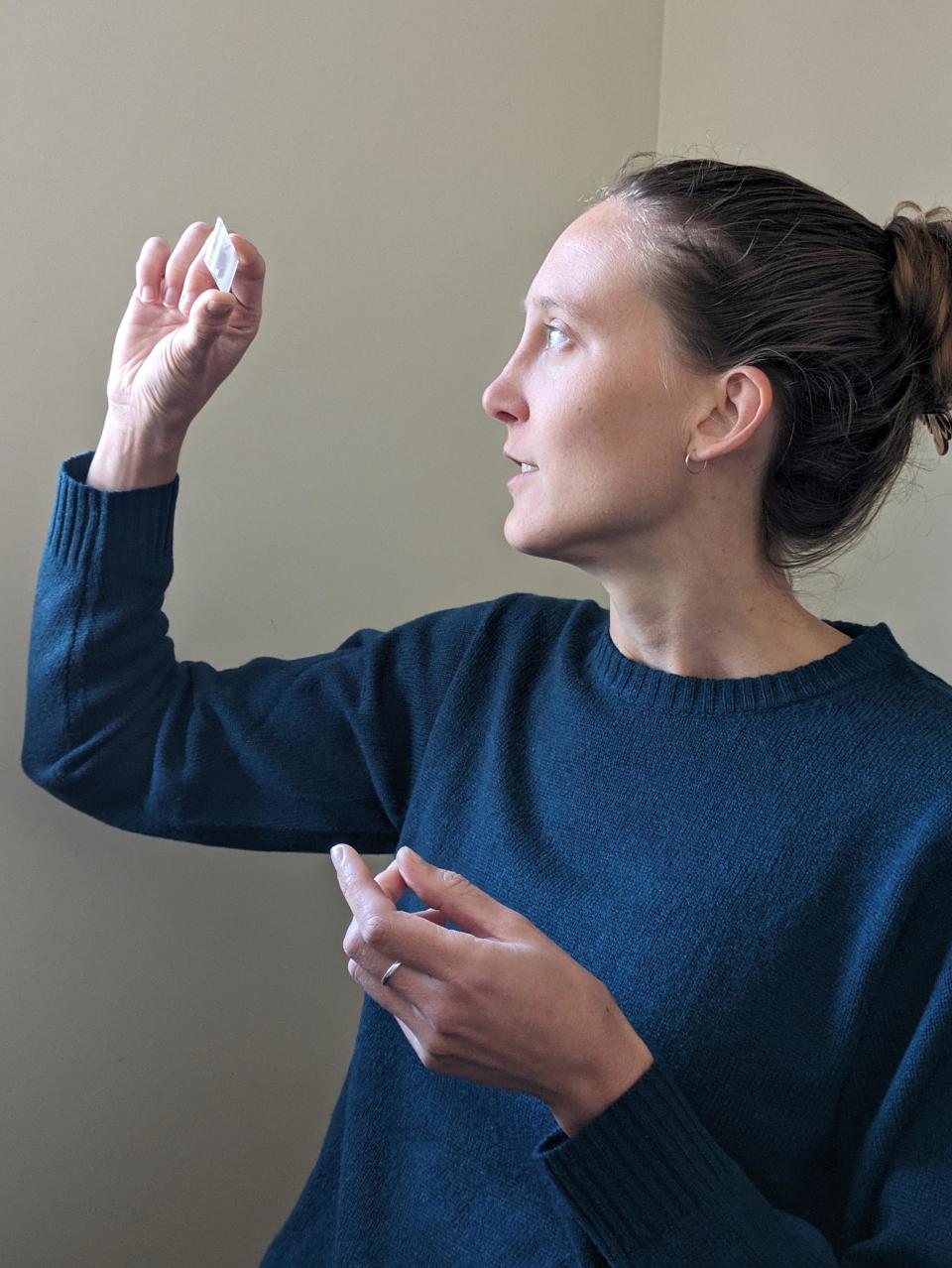 Dr. Erica Barlow in a navy blue sweater looking at the slide containing her stone.